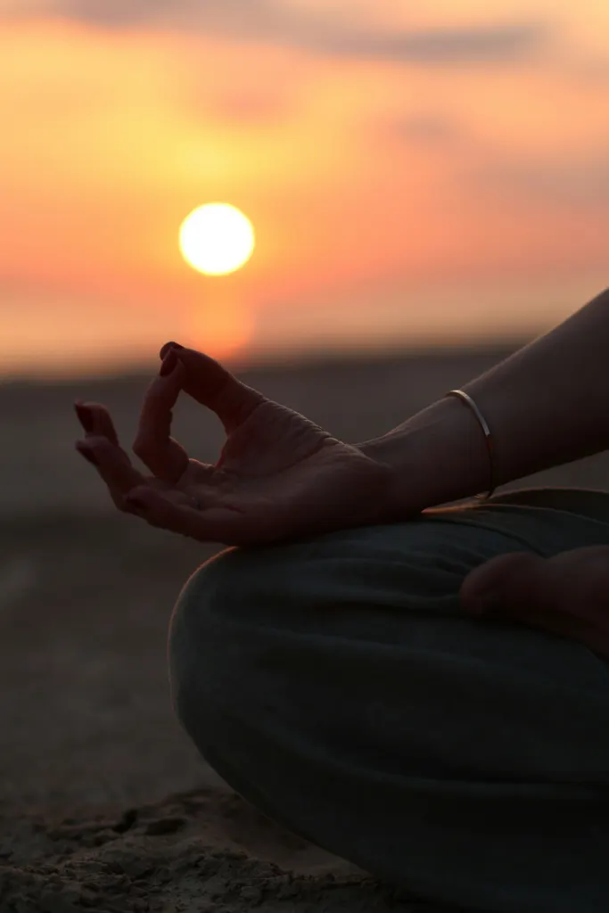 Main en mudra de méditation face au soleil couchant